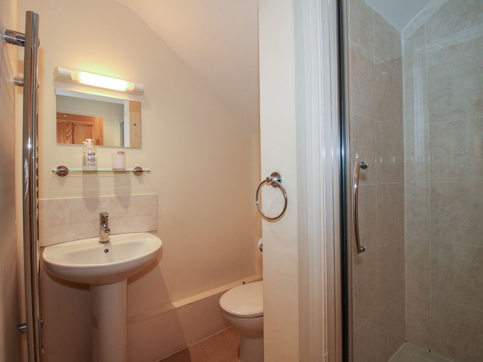A bathroom with a wash basin, toilet, and shower at Wood Cottage in Tenbury Wells