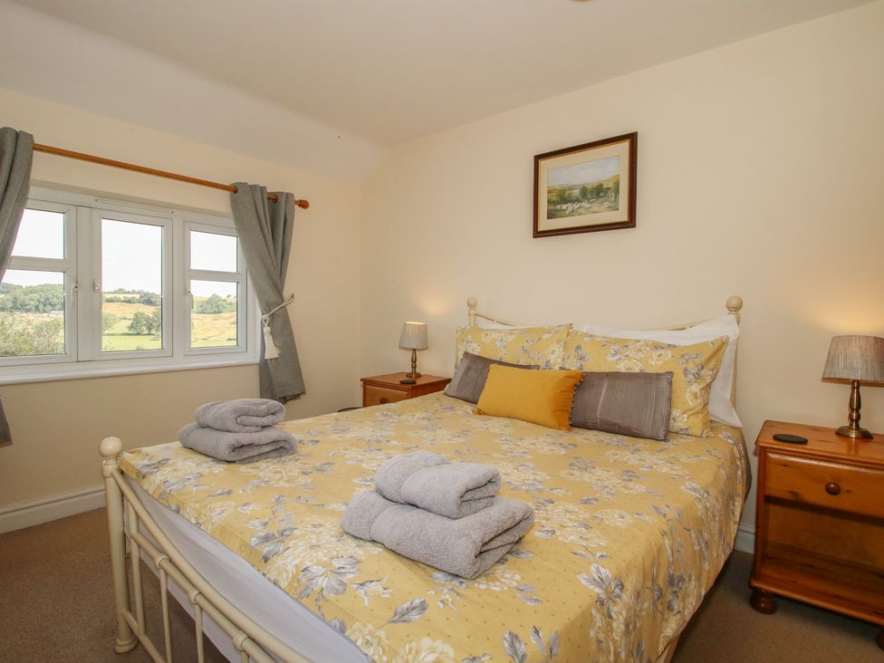 A bedroom with a bed and windows at Wood Cottage in Tenbury Wells