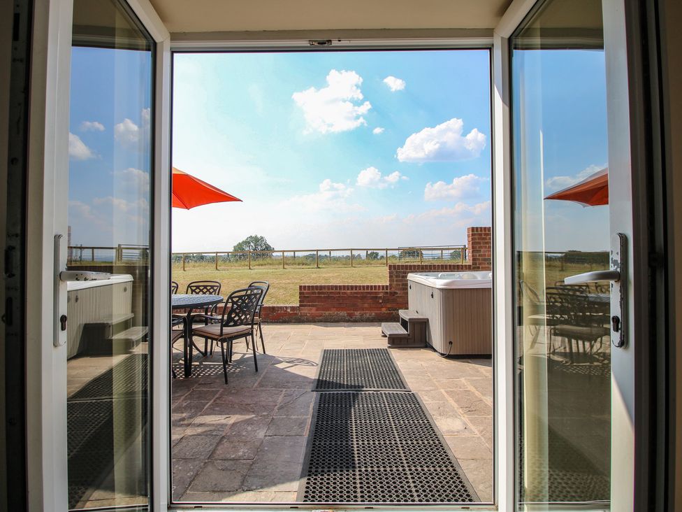 An outdoor area with a patio door leading to a hot tub and seating at Wood Cottage in Tenbury Wells