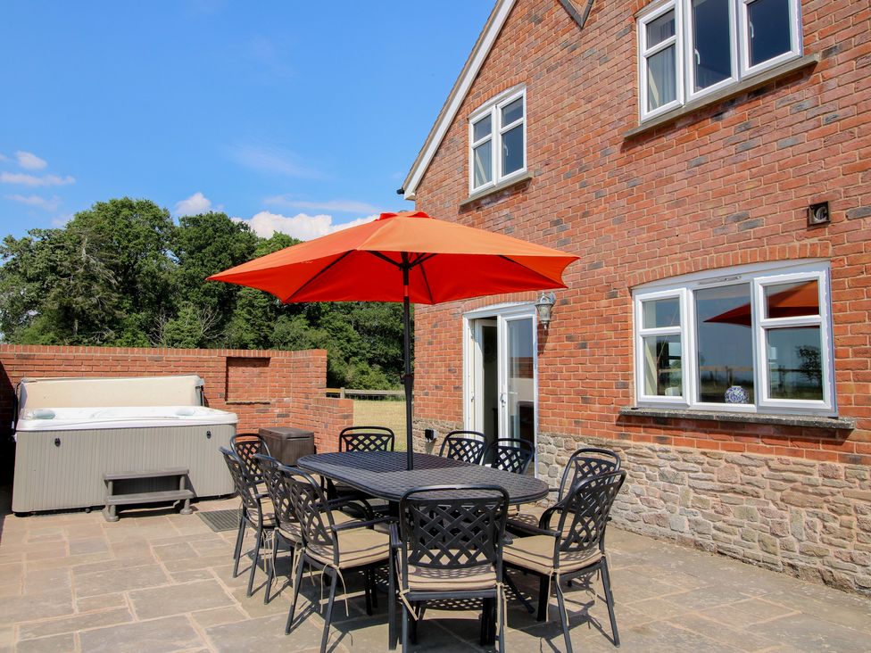 An outdoor area with a table and chairs under an umbrella at Wood Cottage in Tenbury Wells