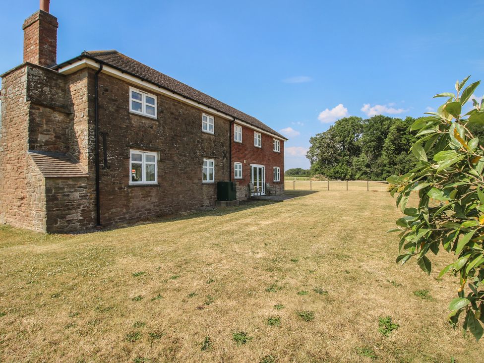 A house with a grassy area and trees at Wood Cottage in Tenbury Wells
