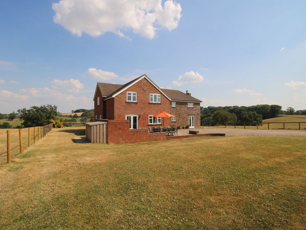 A house with a patio and umbrella at Wood Cottage in Tenbury Wells
