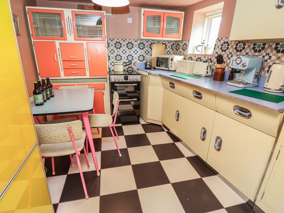 A kitchen with appliances and a table at Dairy Cottage in Whitwell near Niton