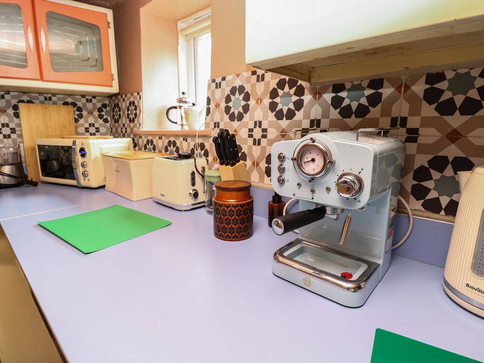 A kitchen with appliances and a chopping board at Dairy Cottage in Whitwell near Niton