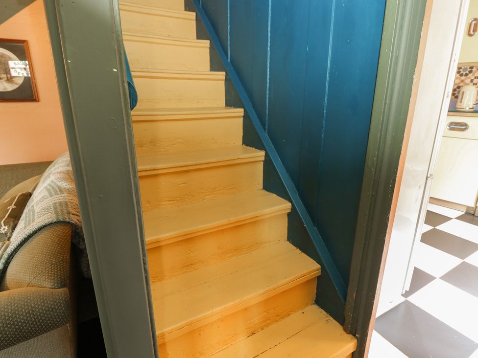 A staircase with yellow steps and a blue wall at Dairy Cottage in Whitwell near Niton