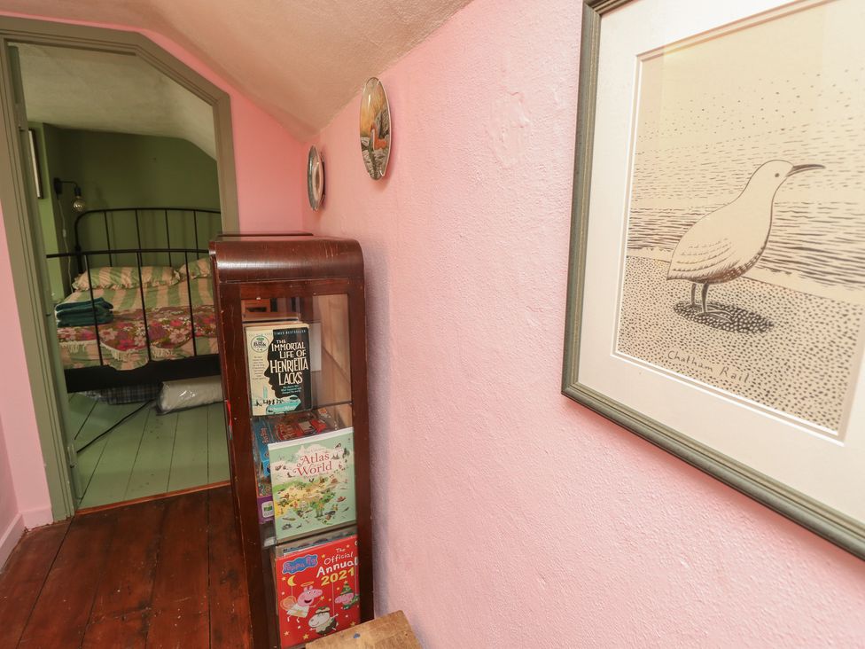 A bedroom with a bed and a bookshelf at Dairy Cottage in Whitwell near Niton
