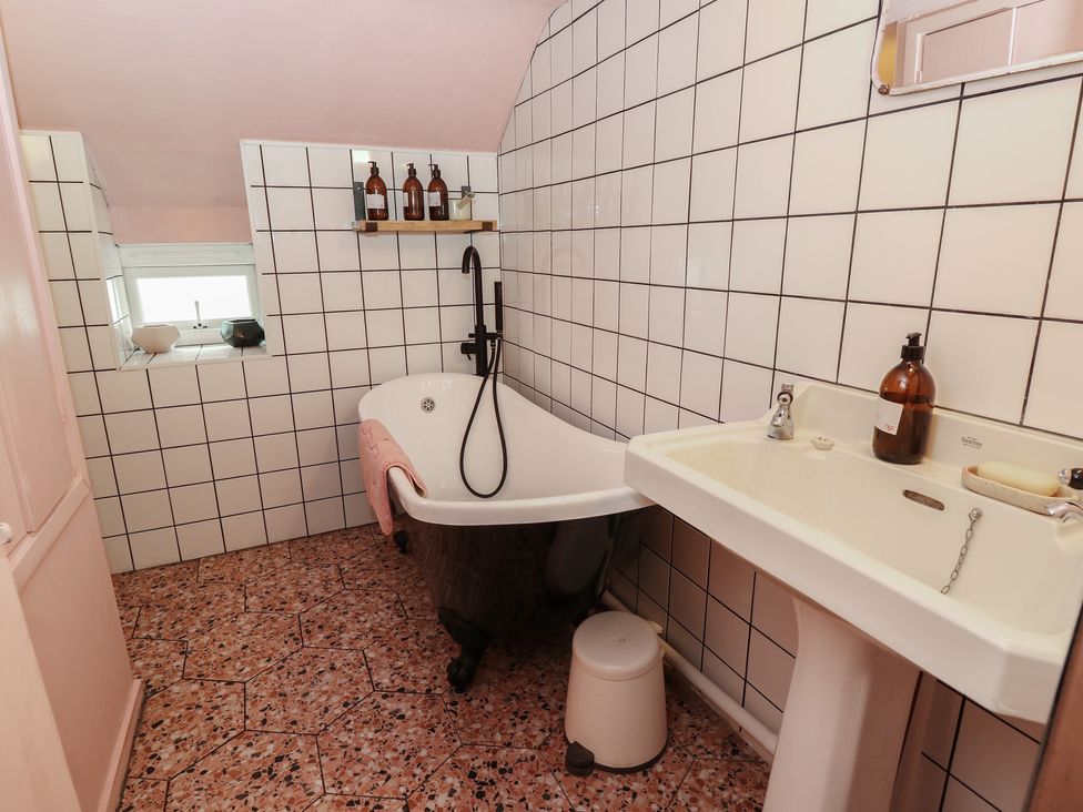 A bathroom with a bathtub and sink at Dairy Cottage in Whitwell near Niton