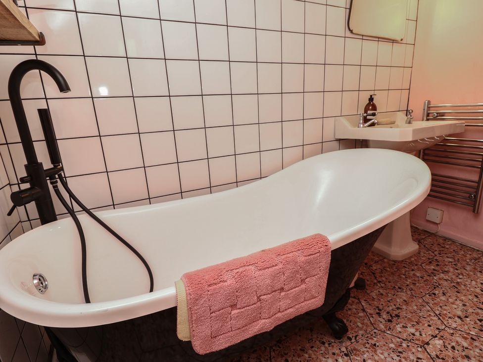 A bathroom with a bathtub and sink at Dairy Cottage in Whitwell near Niton