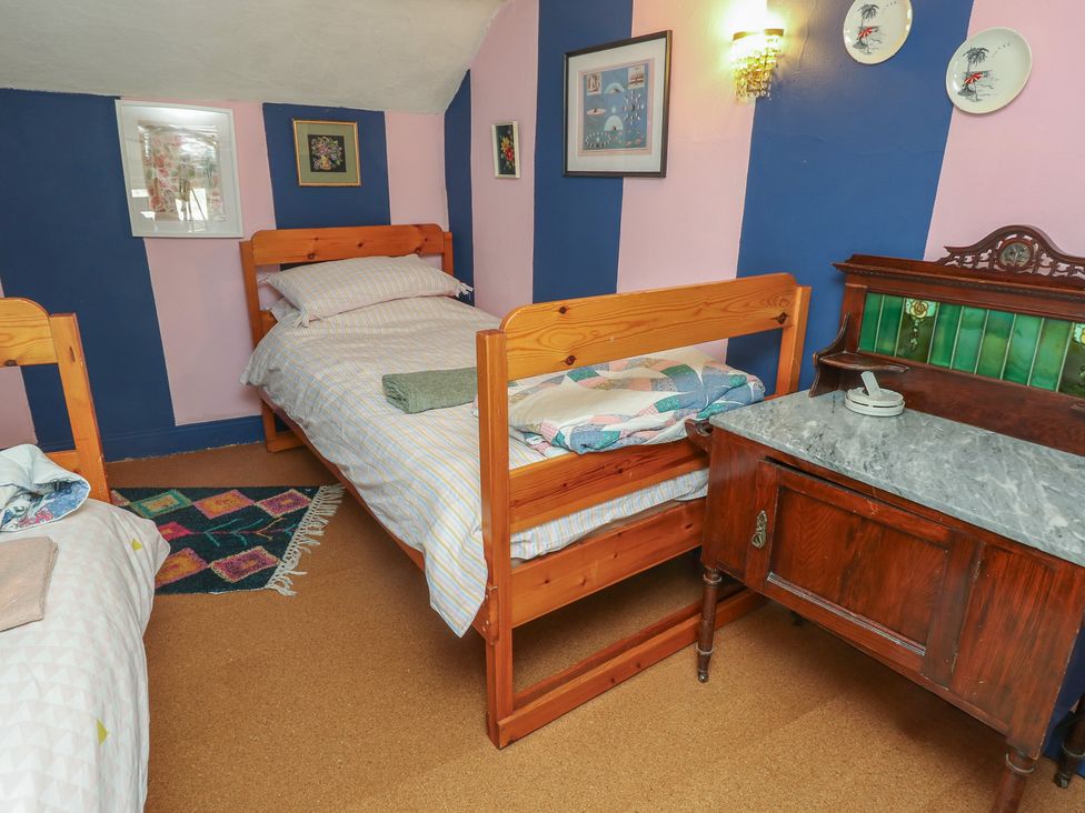 A bedroom with two beds and a wooden table at Dairy Cottage in Whitwell near Niton