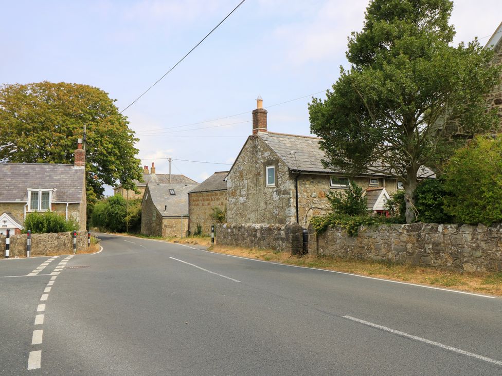 A view of a road with stone houses and trees at Dairy Cottage in Whitwell near Niton