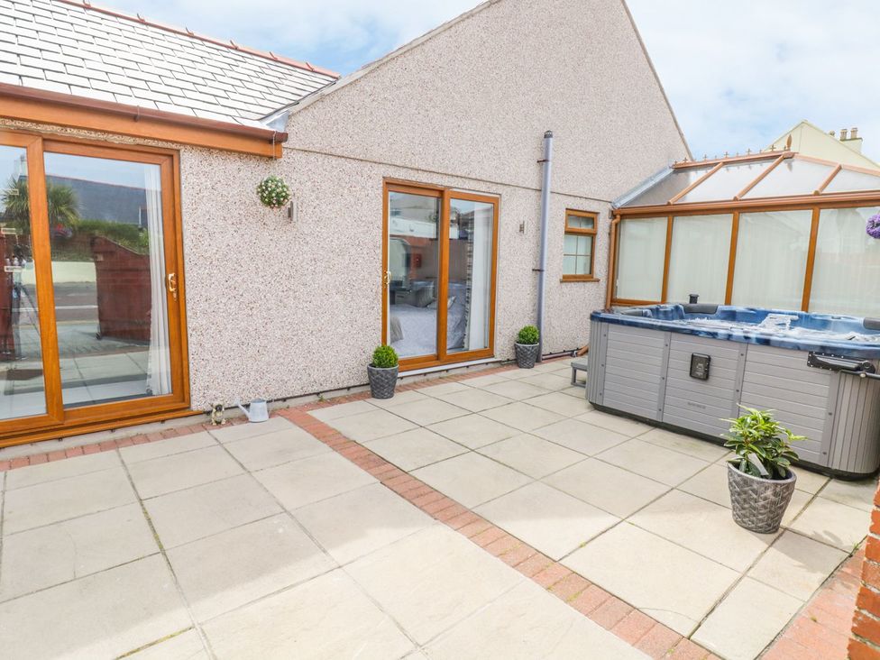 An outdoor area with a hot tub and sliding doors at Smithy Cottage, Cemaes Bay