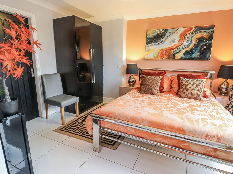 A bedroom with a bed, wardrobe, and chair at Smithy Cottage in Cemaes Bay