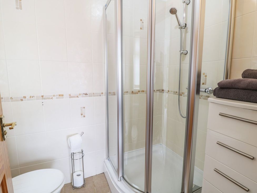 A bathroom with a shower and toilet at Smithy Cottage in Cemaes Bay