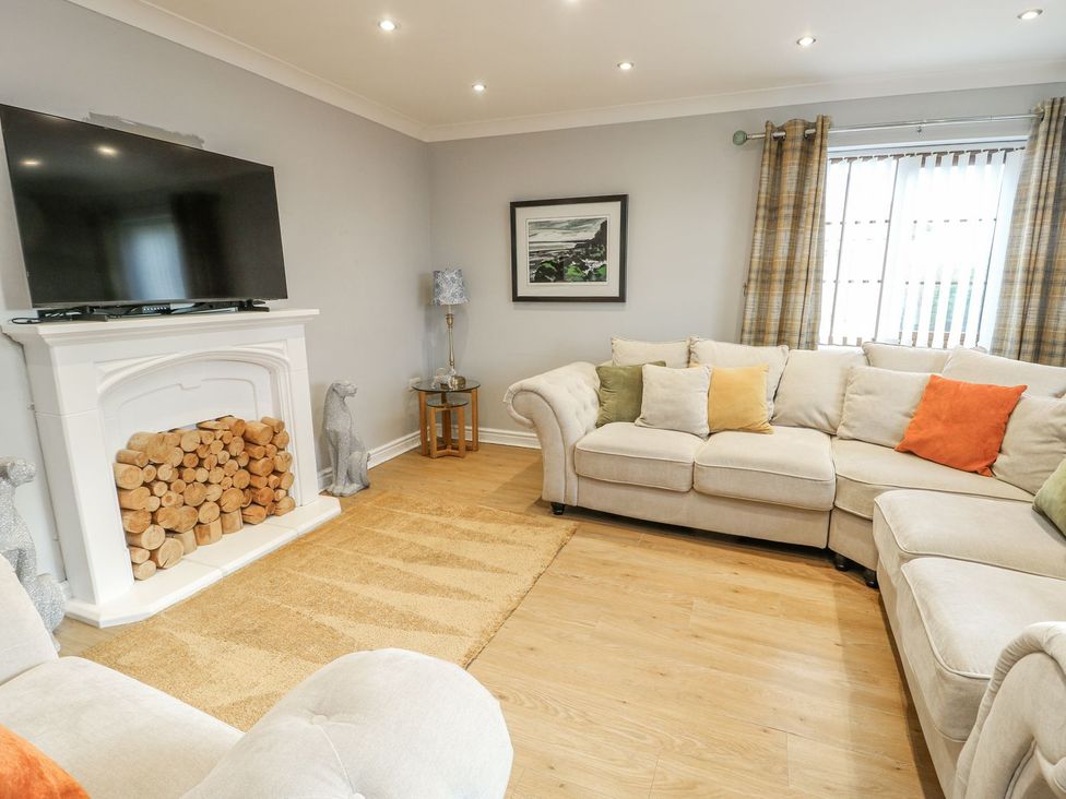 A living room with a television on a fireplace at 1 The Old Smithy Cemaes Bay