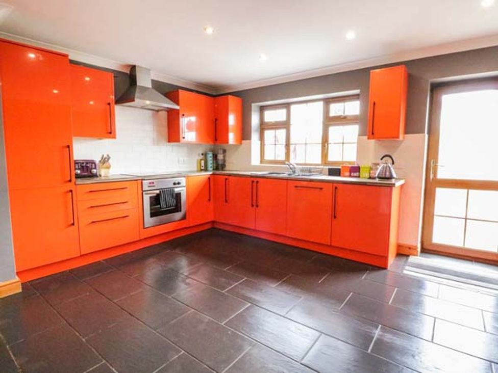 A kitchen with orange cabinets and stainless steel appliances at 1 The Old Smithy Cemaes Bay