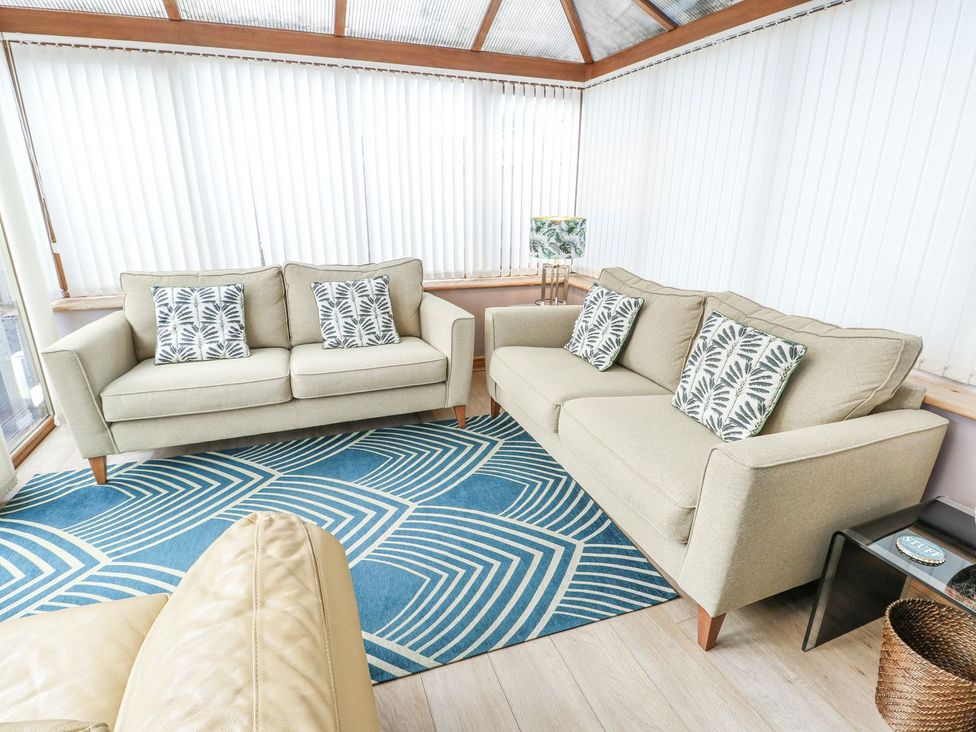 A conservatory with sofas and a rug at 1 The Old Smithy in Cemaes Bay