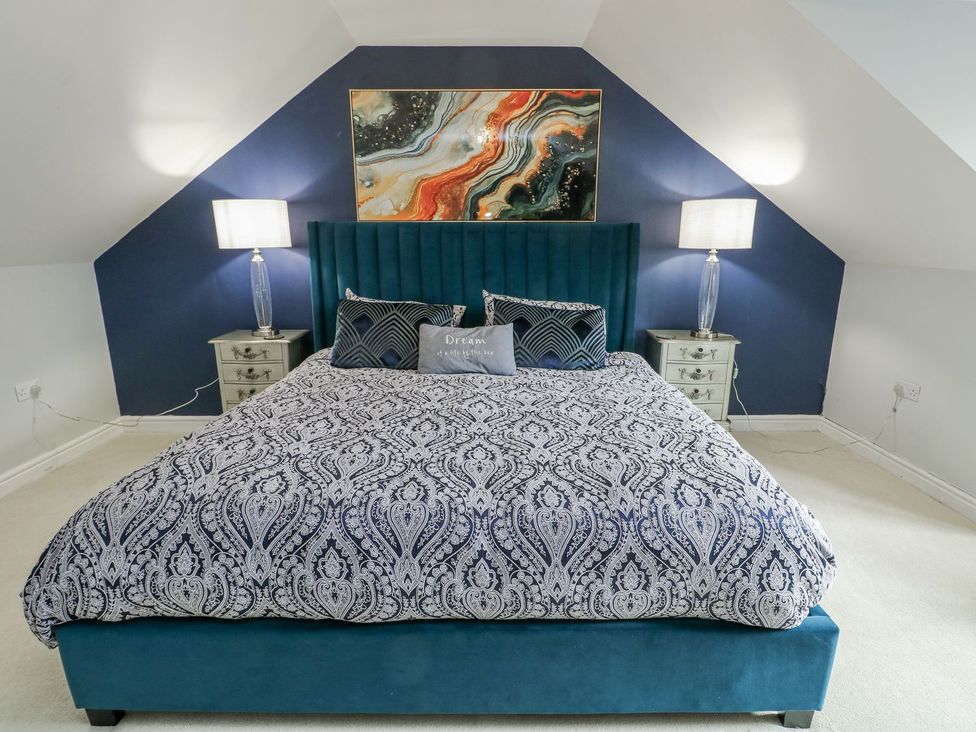A bedroom with a large bed and bedside lamps at 1 The Old Smithy Cemaes Bay