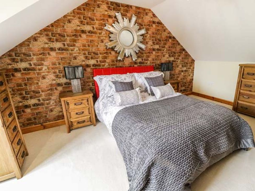 A bedroom with a bed, nightstands, and a mirror at 1 The Old Smithy, Cemaes Bay