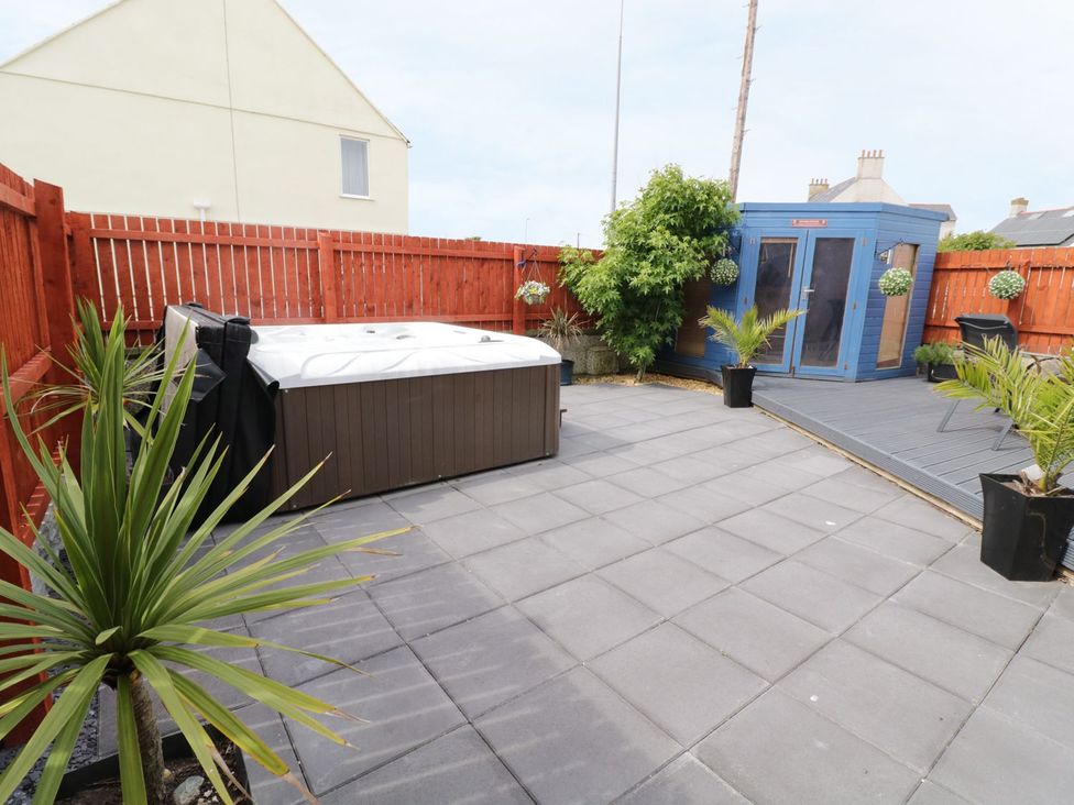A garden with a hot tub, garden shed, and potted plants at 1 The Old Smithy in Cemaes Bay