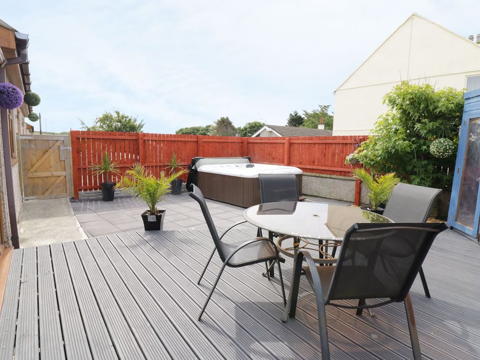 A patio with a hot tub and table with chairs at 1 The Old Smithy Cemaes Bay
