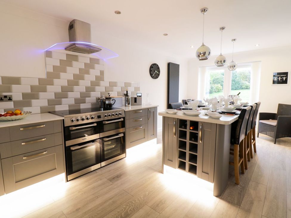 A kitchen with an island, stove, and dining area at Gwelfor in Cemaes Bay