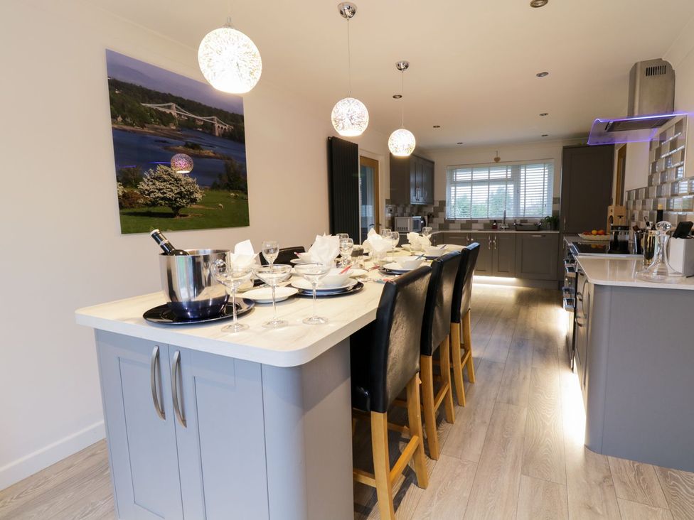 A kitchen with bar stools and dining table at Gwelfor in Cemaes Bay