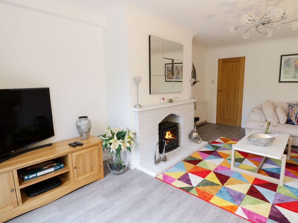 A living room with a television, sofa, and fireplace at Gwelfor in Cemaes Bay