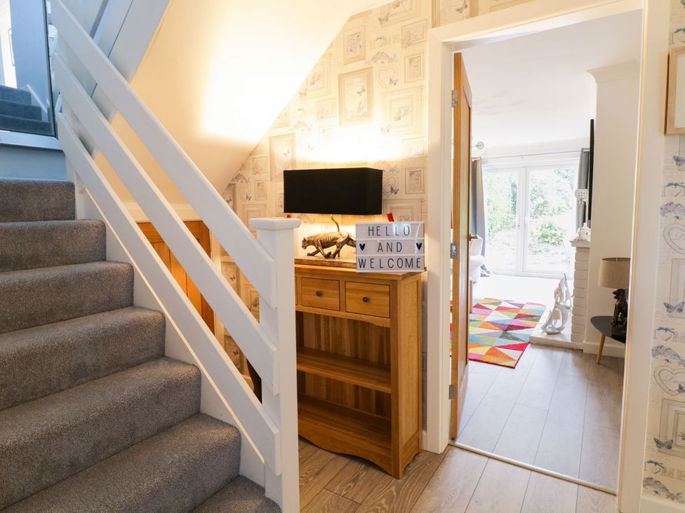 A hallway with stairs, a console table and a decorative sign at Gwelfor in Cemaes Bay