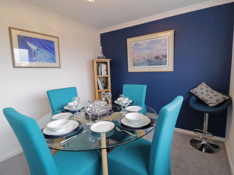 A dining room with a glass table and blue chairs at Gwelfor in Cemaes Bay