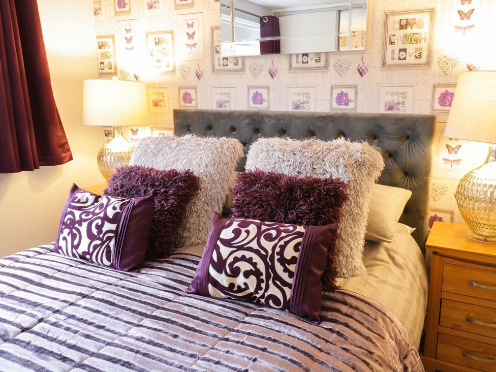 A bedroom with a bed, pillows, and lamps at Gwelfor in Cemaes Bay