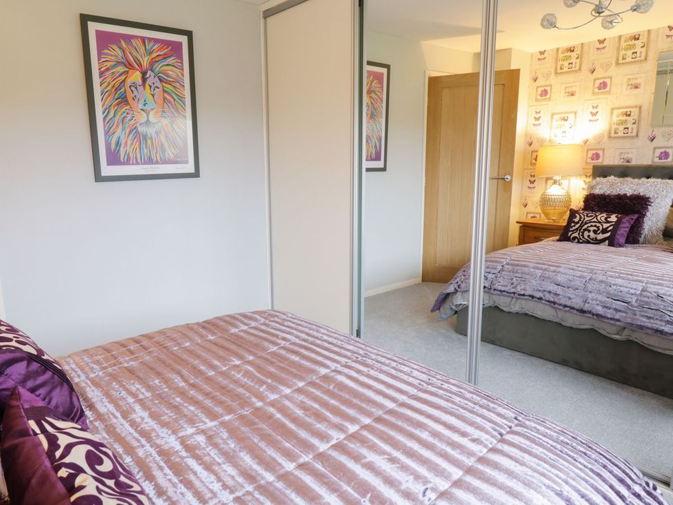 A bedroom with a bed, wardrobe, lamp and artwork at Gwelfor in Cemaes Bay
