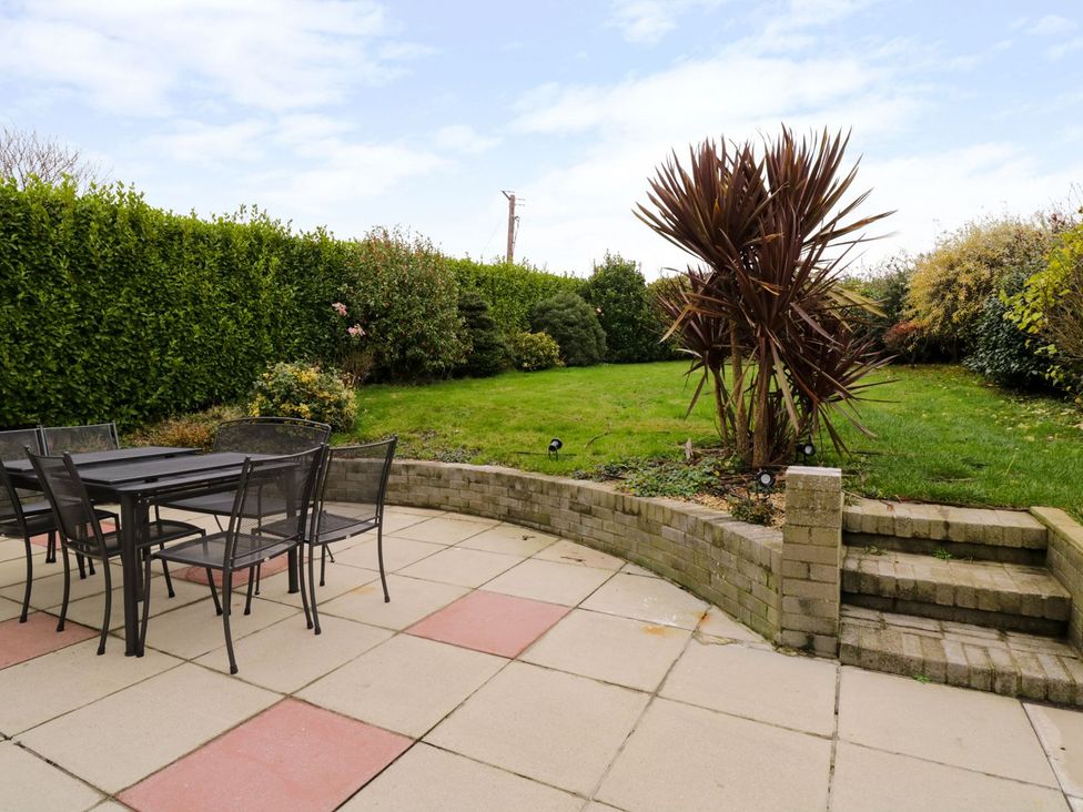 A garden with a patio set and landscaped greenery at Gwelfor Cemaes Bay