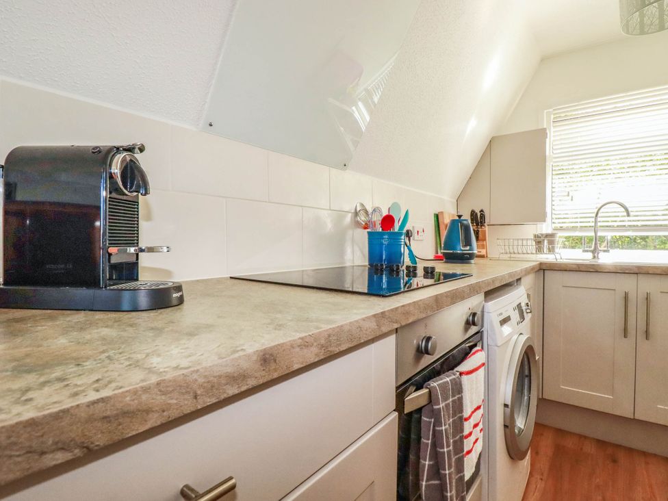 A kitchen with a stove and washing machine at Coombe Lodge No 9 Bude