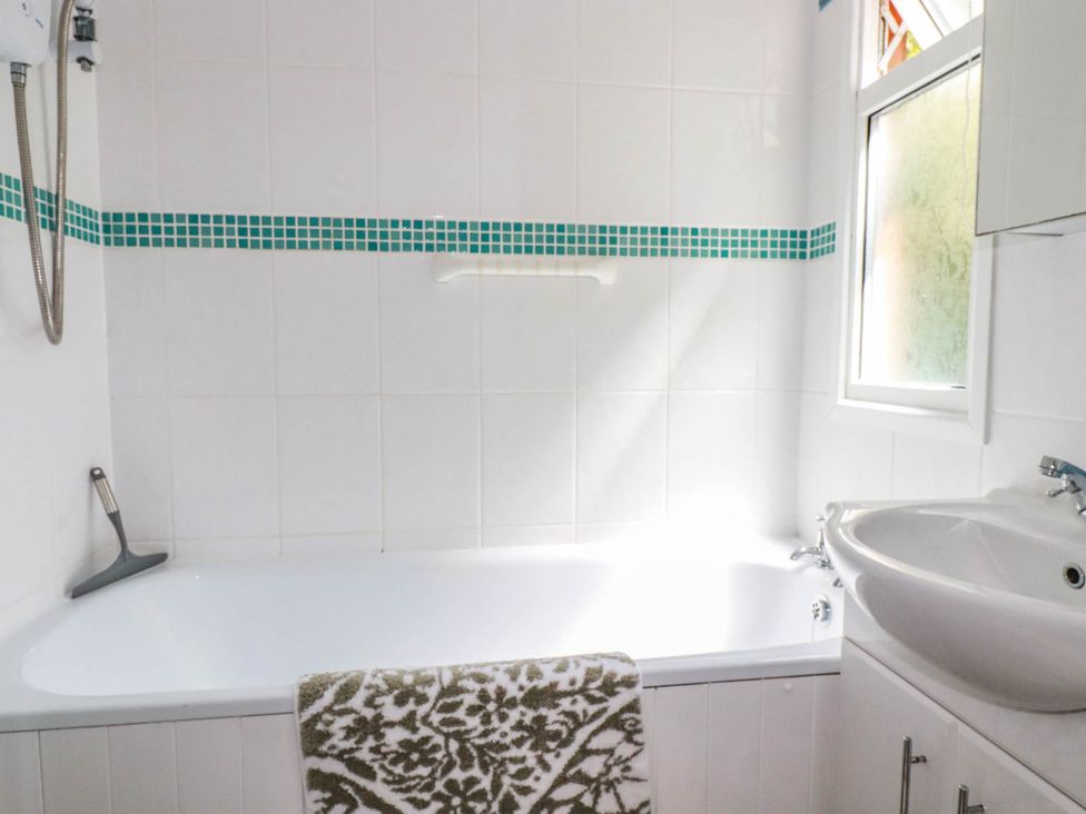 A bathroom with a bath tub and sink at Coombe Lodge No 9 in Bude