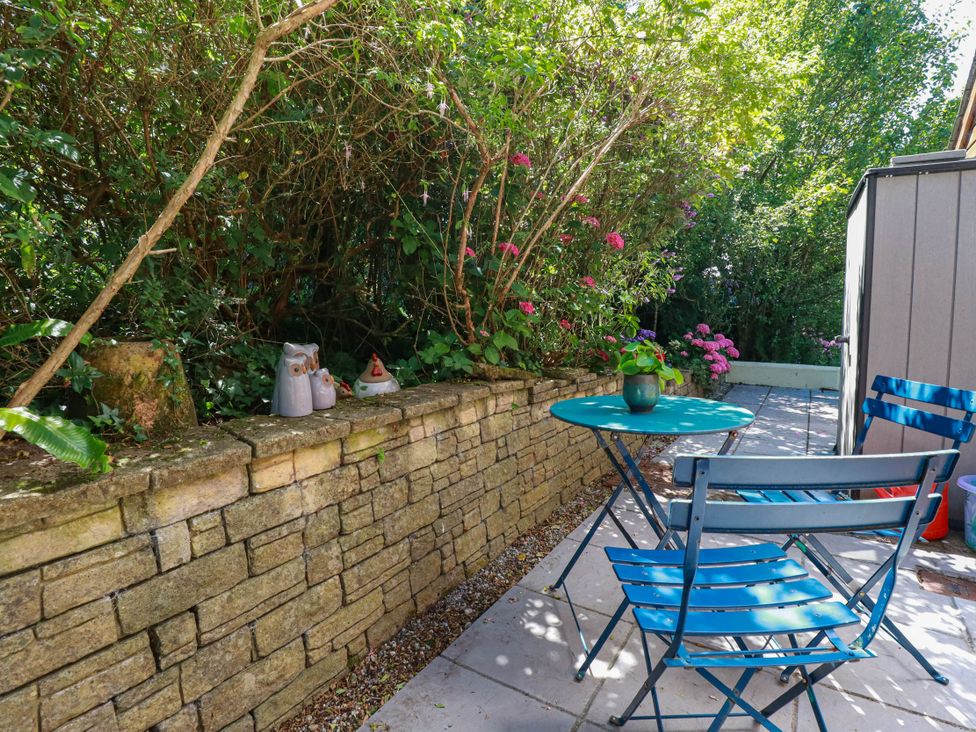 A garden with a stone wall, table, and chairs at Coombe Lodge No 9 in Bude
