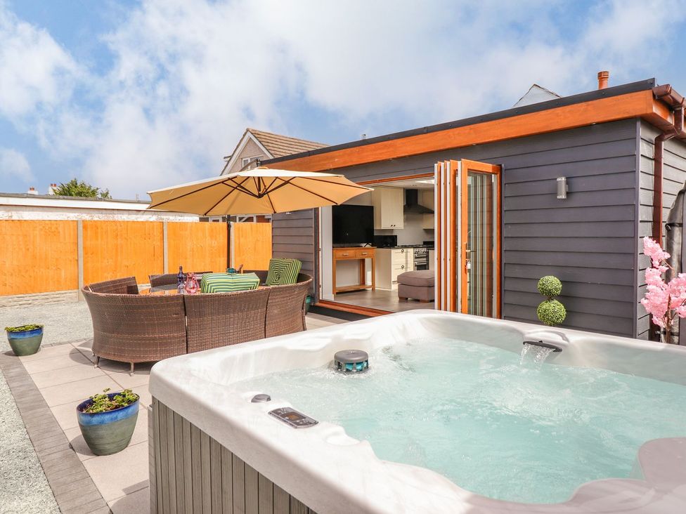 An outdoor area with a hot tub and seating at Trefin Cemaes Bay