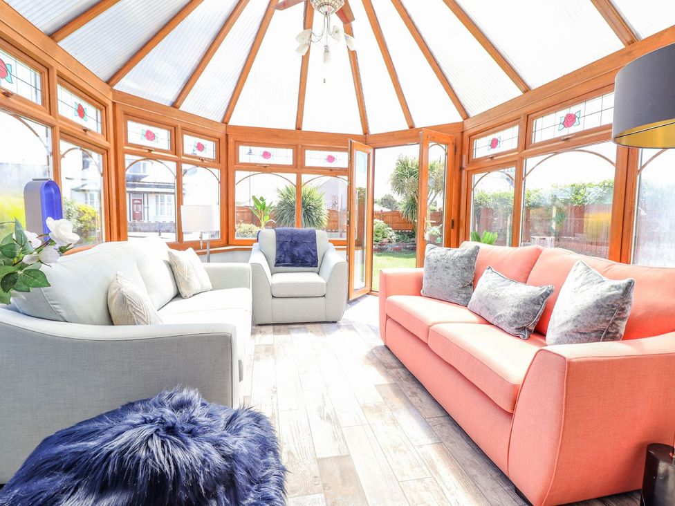 A conservatory with sofas and plants at Trefin in Cemaes Bay