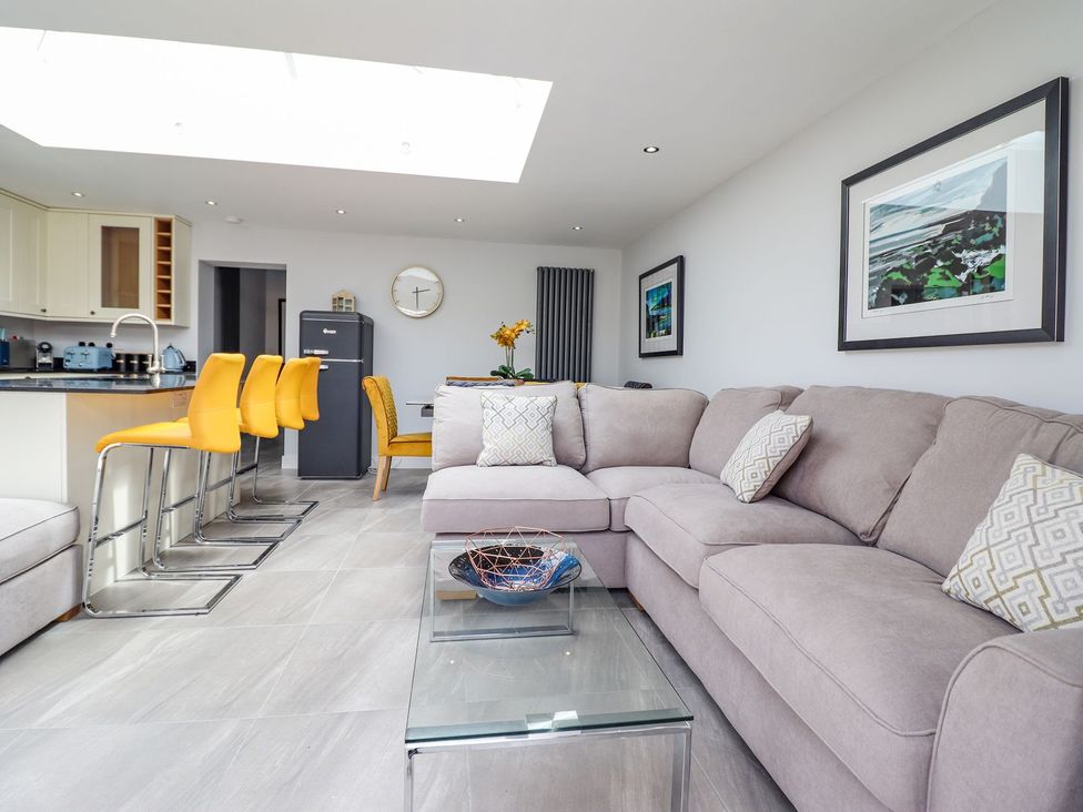 A living room with a sofa, coffee table and kitchen island at Trefin in Cemaes Bay
