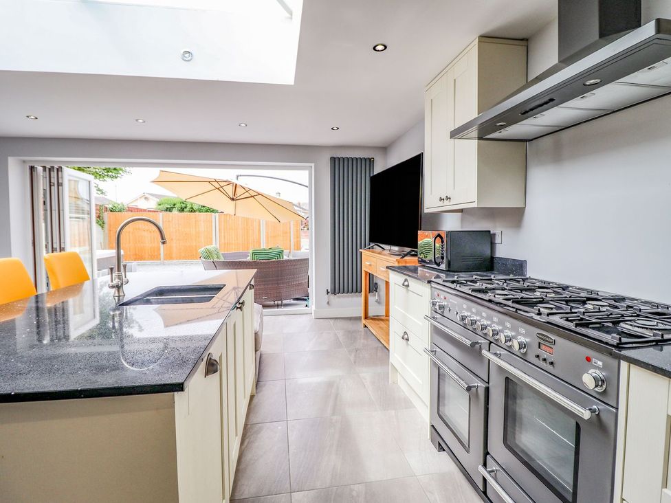 A kitchen with a stove, sink, and television at Trefin in Cemaes Bay