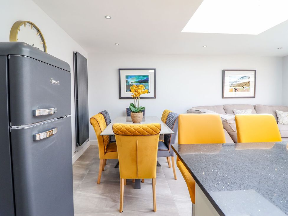 A kitchen with a dining area featuring a table and yellow chairs at Trefin in Cemaes Bay