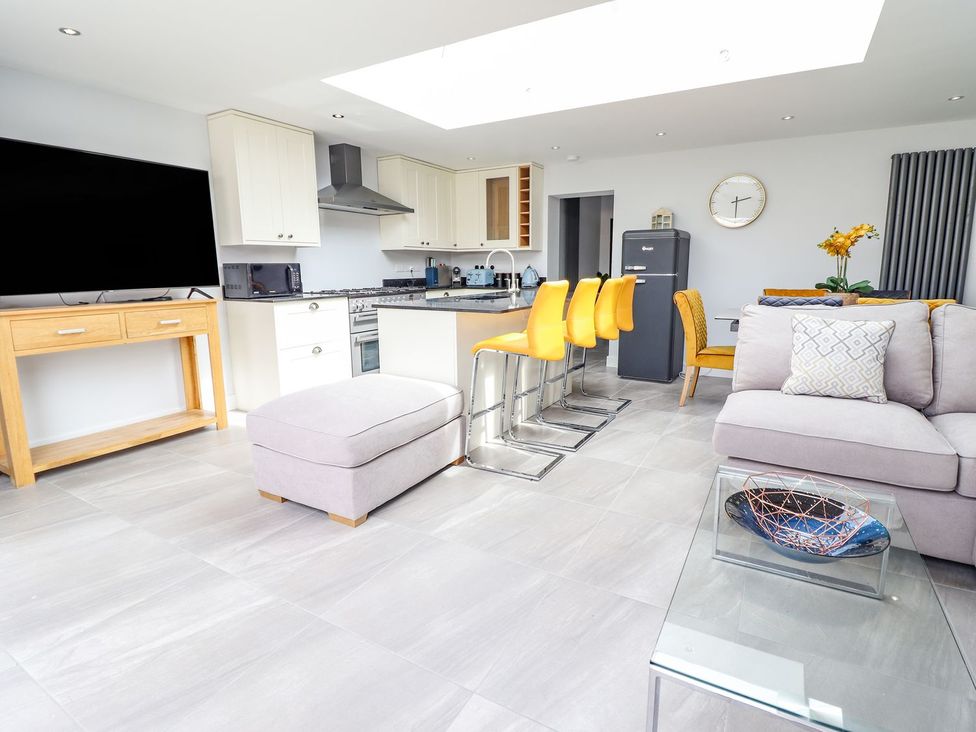 A living room with a kitchen island and bar stools at Trefin in Cemaes Bay
