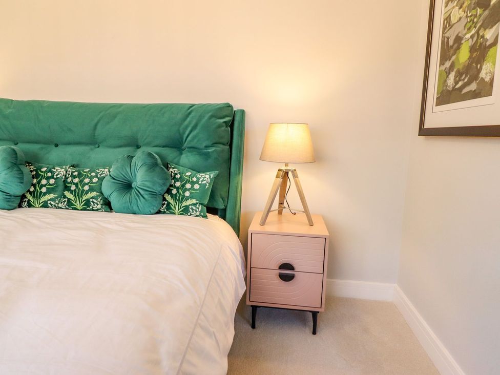 A bedroom with a green headboard and pink nightstand at Trefin in Cemaes Bay
