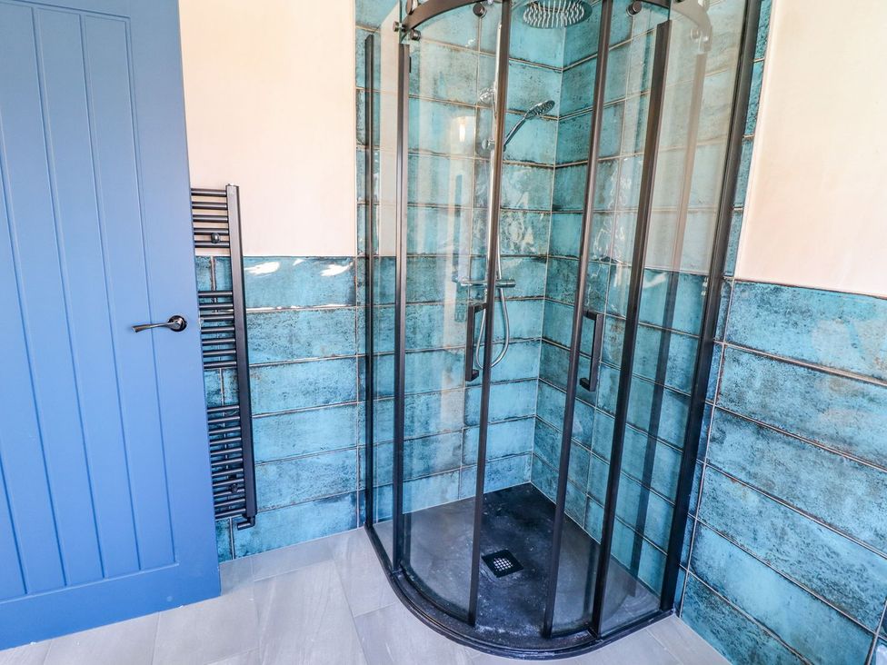 A shower with glass enclosure and towel radiator at Trefin in Cemaes Bay