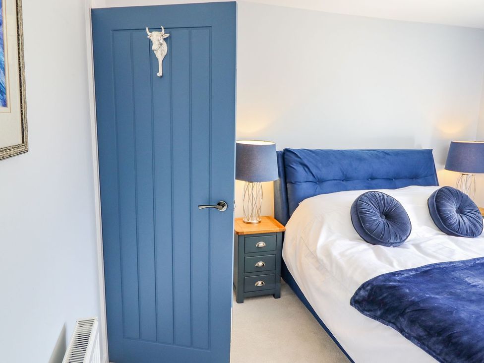 A bedroom with a blue door and a bed at Trefin in Cemaes Bay