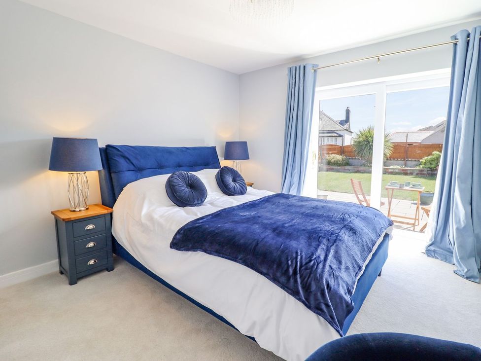 A bedroom with a bed and garden view at Trefin Cemaes Bay