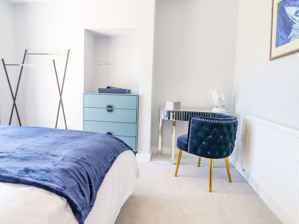 A bedroom with a bed and a chair at Trefin in Cemaes Bay