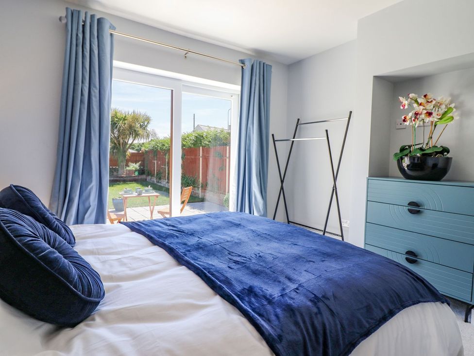 A bedroom with a bed and windows overlooking a garden at Trefin in Cemaes Bay