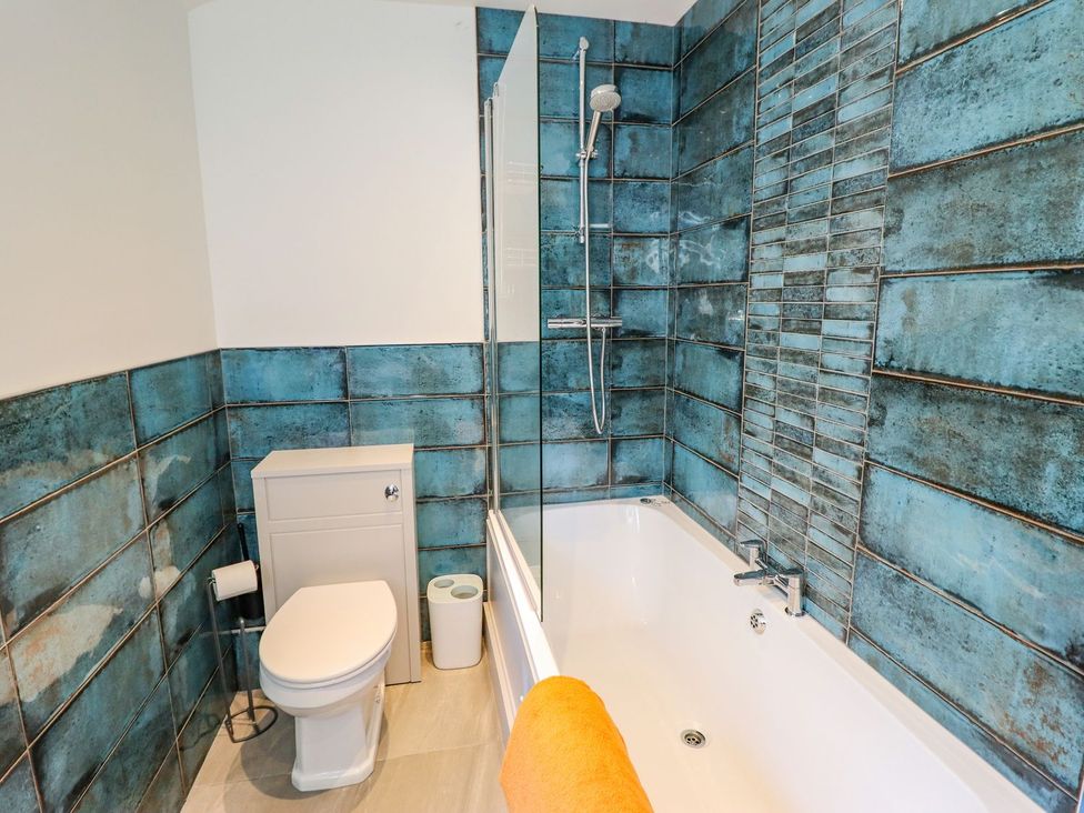 A bathroom with a bathtub, toilet, and shower at Trefin, Cemaes Bay