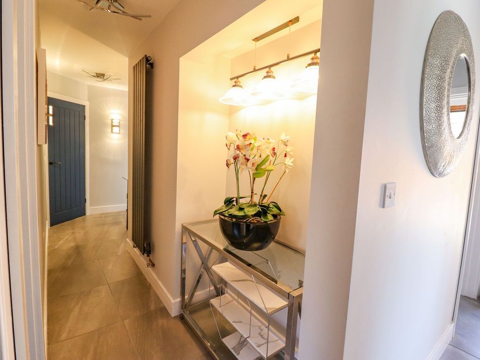 A hallway with a table and a vase of flowers at Trefin in Cemaes Bay