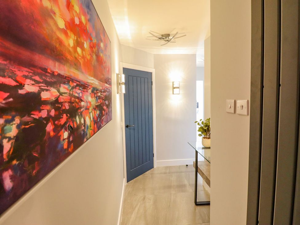 A hallway with a painting, door, and table at Trefin Cemaes Bay
